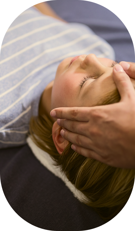 child laying on their back with adult hands on their head